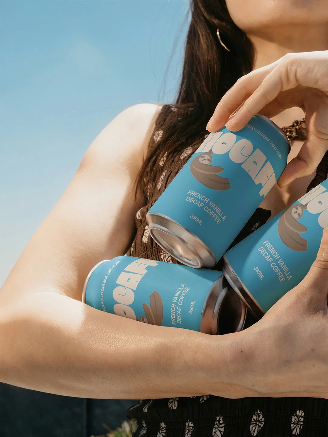 Nocaff Cans Held in Person's Arms